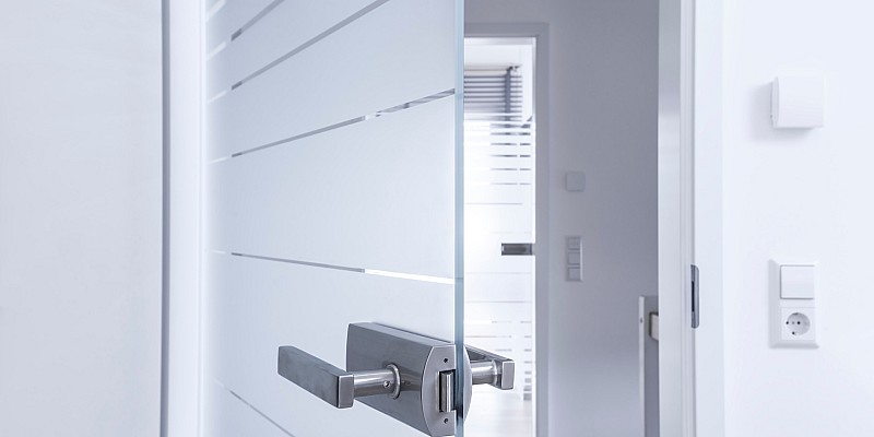 Teilgeöffnete Glastür mit satiniertem Streifendekor in modernem Innenraum.